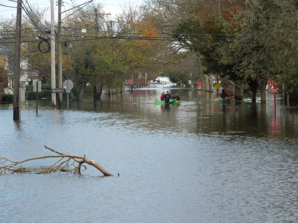 Kayakers paddle down a flooded neighborhood street.